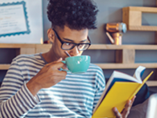 Young man reading a book while sipping coffee 